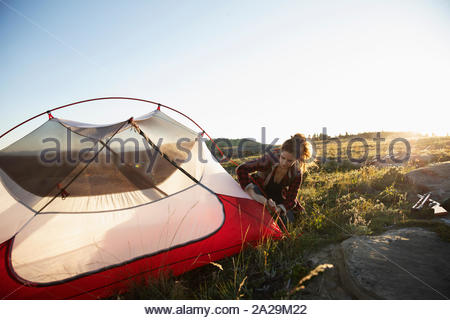 Junge Frau pitching Zelt auf Gras im Sonnenlicht