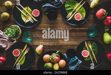 Herbst Tabelle Styling für Urlaub Abendessen. Flachbild-schwarz Geschirr mit Früchte und Blätter für die Dekoration auf rustikalen Holztisch lag, Ansicht von oben, Kopieren spac Stockfoto