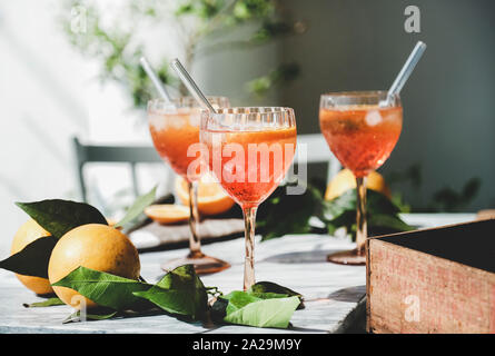 Aperol Spritz aperitif Alkohol kalte Getränke in Gläsern mit frischen Orangen und Eis auf grauem Marmor, selektiver Fokus, Nahaufnahme. Sommer erfrischende dri Stockfoto