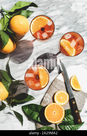 Aperol Spritz aperitif Alkohol kalte Getränke in Gläsern mit Orangen und Eiswürfel in grauem Marmor Tabelle, Ansicht von oben. Sommer erfrischendes Getränk Konzept Stockfoto