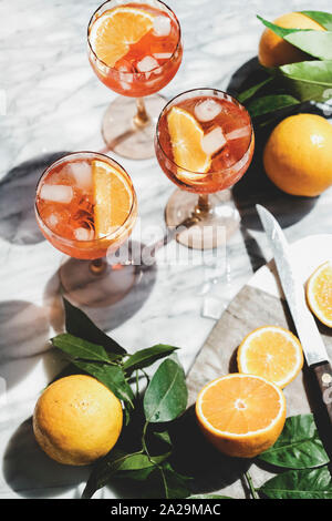 Aperol Spritz aperitif Alkohol kalte Getränke in Gläsern mit Orangen und Eis über grauem Marmor Tabelle, Ansicht von oben. Sommer erfrischendes Getränk Konzept Stockfoto