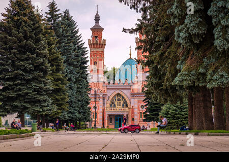 Wladikawkas, Russland - 07. 18. 2019: Menschen, die Ruhe auf dem Platz unter schönen alten Kiefern vor sunnitischen Moschee Mukhtarov Stockfoto