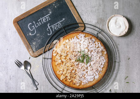 Glutenfreie Mandel Rosmarin hausgemachte Kuchen mit Mandeln und Zucker Puder auf Kühlung Rack dekoriert, mit Sauerrahm und vintage Tafel über gr steht für: Stockfoto