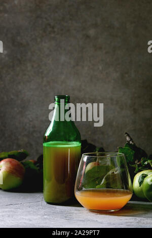 Flaschen ang Glas Apfelwein mit niedrigem Alkohol trinken mit Garten Äpfel mit Blättern und Zweigen auf Tabelle mit dunklem Hintergrund. Herbst home Ernte. Stockfoto