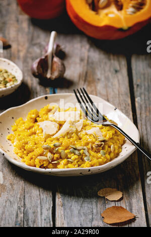 Traditionelle vegetarische Kürbis risotto italienischen Gericht in Keramikplatte auf alten hölzernen Küchentisch mit Zutaten oben. Im rustikalen Stil Stockfoto