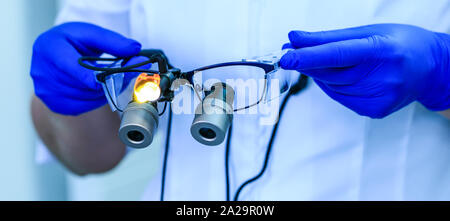 Echten zahnmedizinische Arzt hält die medizinische Gläser mit Fernglas Linsen, in der Zahnheilkunde Klinik. Zahnarzt Brille oder zahnmedizinische Optik auf einem Hospital Medical laborat Stockfoto