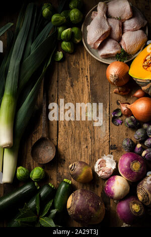 Raw winter Gemüse und Huhn für die Suppe zubereitet werden. Sie sind auf eine rustikale Holz Hintergrund mit einem Vintage rustikalen Löffel angezeigt. Stockfoto