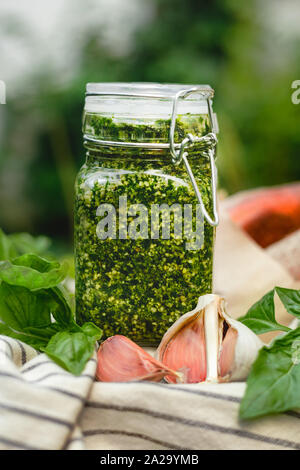 Pesto in einem Glas in ein Picknick im Freien. Pesto - Traditionelle italienische Soße für Fettuccine, Focaccia, Pizza, Toast, Sandwiches, Bruschetta. Stockfoto