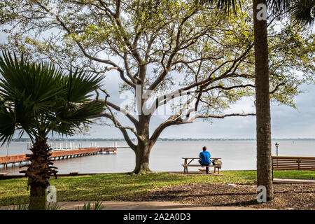 Ein Mann sitzt entlang des Stuart Boardwalk in Flagler Park in der historischen Innenstadt in Stuart, Florida. Der winzige Weiler wurde im Jahr 1870 gegründet und war der glücklichste Stadt am Meer in Amerika von Küste gestimmt. Stockfoto