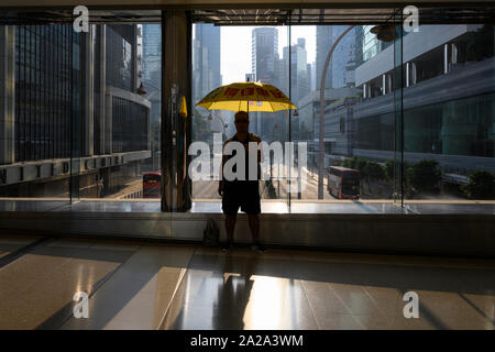 2. Oktober 2019. Hongkong setzt Business am Morgen nach der gewaltsamen Proteste am 1. Oktober 2019. Ein Mann steht schweigend auf einer Fußgängerbrücke in Admiralty Hong Kong mit einem gelben Schirm am Morgen nach der gewaltsamen Auseinandersetzungen und Proteste in Hongkong. Stockfoto