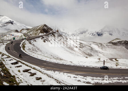 Motorräder und Autos auf dem Großglockner Pass in der Region Tirol in Österreich im Frühsommer, mit Schnee auf dem Berg Stockfoto