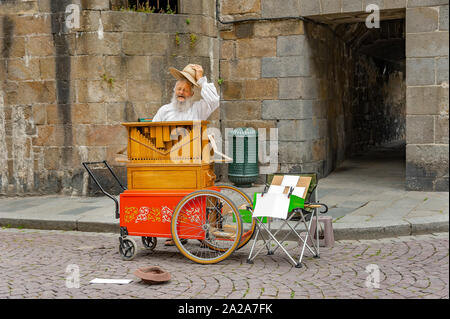 Saint-Malo, Frankreich - 20. Juli 2017: Alter Mann mit langen weißen Brot steht hinter seiner Straße Orgel singen, während sein Musikinstrument für Tipps. Stockfoto