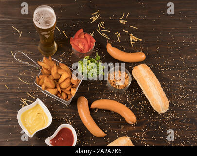 Heiße Hunde Gemüse, Soßen und Keile Pommes auf hölzernen Tisch Stockfoto