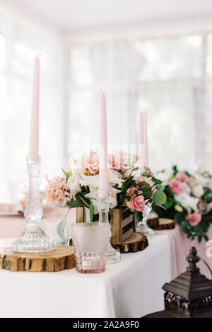 Hochzeit Einrichtung in sanften Farbtönen und natürlichen Materialien. Blass rosa Kerzen in hohen Glas Kerzenhalter Stockfoto