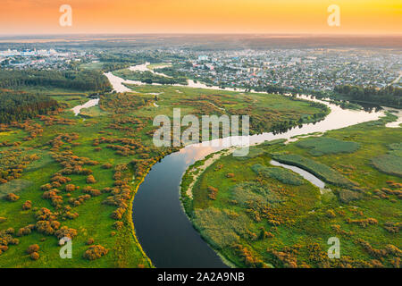 Belarus. Luftaufnahme grüne Wiese und Flusslandschaft in der Nähe der kleinen Stadt im sonnigen Frühling Abend. Blick von oben auf die schöne Natur von hohen Attitud Stockfoto