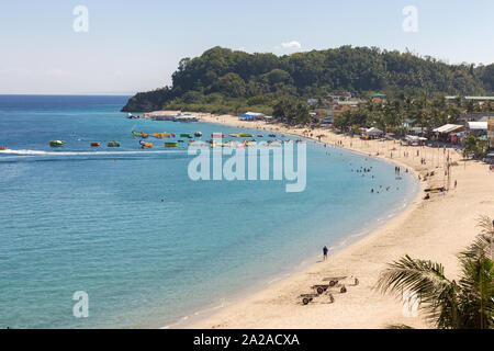 Puerto Galera, Philippinen - April 4, 2017: Meer, blauer Himmel, Palmen, Touristen und Boote in weißen Strand, Sabang. Stockfoto