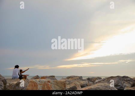 Colombia Riohacha Menschen schwimmen und entspannen am Strand. Das Sitzen auf den Felsen beobachten Sonnenuntergang 26-6-2019 Foto Jaco Klamer/Alamy Stockfoto