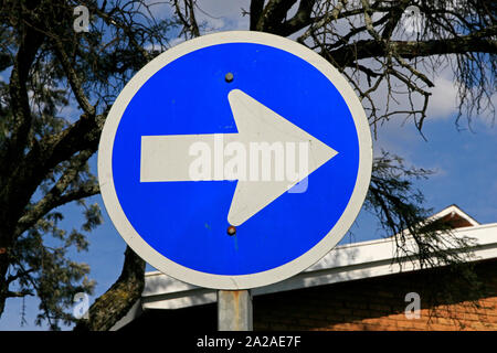 Rechte Pointing blau Richtung Verkehrsschild außerhalb Lynwood Katholische Kirche, IEC Pretoria Wahllokale, Border Road East, Lynwood, Pretoria, Gauteng Provinz, Südafrika. Stockfoto