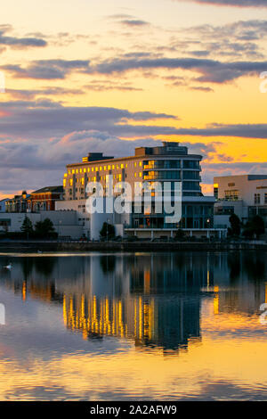 Southport, Merseyside. UK Wetter. 2. Oktober, 2019. Wetter; gedämpften Farben in der Morgendämmerung über dem Resort Marine Lake und renommierte Ramada Plaza Hotel an der Uferpromenade am See Entertainment Complex mit Reflexionen im noch ruhigen Bedingungen. Credit: MediaWorldImages/AlamyLiveNews. Stockfoto