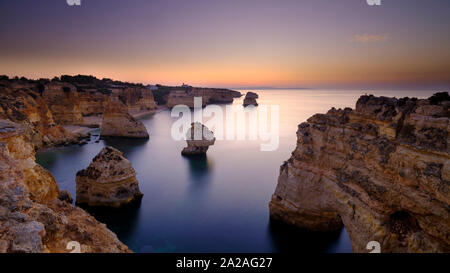 Faro, Portugal - 18. September 2019: Blaue Stunde Sonnenaufgang und entlang der Küste der Algarve in Richtung Faro von den Klippen oberhalb von Praia da Marinha, Portugal Stockfoto