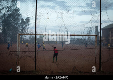 Junge Männer spielen ein Fußballspiel in einem Pitch voll Rauch von dandora Deponie, im Slum Korogocho in der Hauptstadt Nairobi, Kenia. Stockfoto