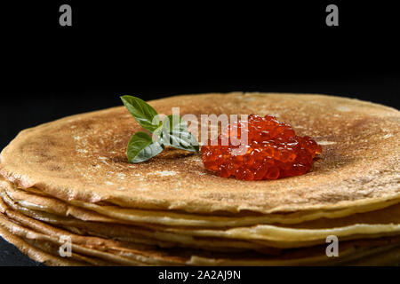 Stapel Pfannkuchen mit roter Kaviar auf schwarzem Hintergrund, in der Nähe Stockfoto