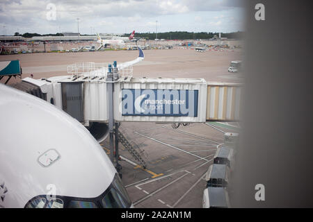 Ein Flugzeug, das am Flugsteig am Flughafen Manchester, Großbritannien, geparkt wurde. Hauptaugenmerk auf dem Gehweg neben dem Flugzeug für Passagiere zum ein- und Aussteigen. Stockfoto