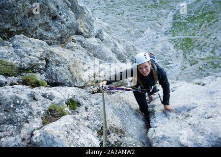 Attraktiven weiblichen Bergsteiger in den Dolomiten in Südtirol auf den steilen und schwierigen Poessnecker Klettersteig Stockfoto