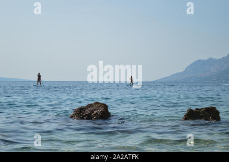 Paar Stand Up Paddling am Strand von Brela, Kroatien Stockfoto