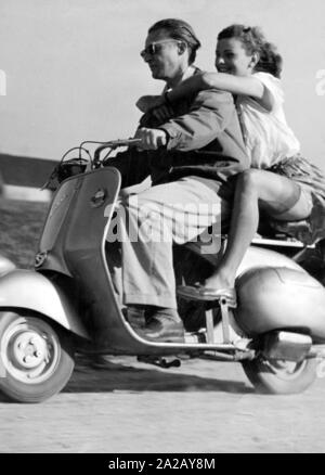 Ein junges Paar Laufwerke auf einem Motorroller der Marke Verspa. Stockfoto