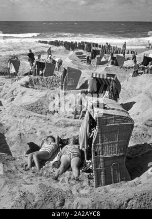 Die Badenden sonnen oder sitzen in ihren Liegen am Strand von Westerland auf der Insel Sylt. Stockfoto