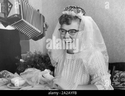 Eine Braut in Stalinstadt, DDR. Sie hält einen Brautstrauß, links einen Musiker auf einem Akkordeon spielt. Stockfoto