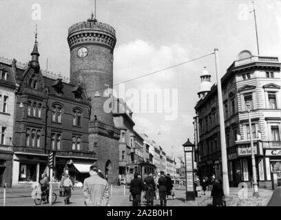 Blick auf den Spremberger Turm und der angrenzenden Gebäude in der Innenstadt von Cottbus. Im Vordergrund stehen viele Passanten, in der Mitte des Bildes eine Straßenbahn vorbei ist. Der spremberger Turm ist das Wahrzeichen von Cottbus, als Tor Turm seine Geschichte geht zurück bis in das 13. Jahrhundert betrachtet. Stockfoto