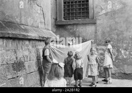 Kinder beobachten ein Puppenspiel an einer Hauswand in Würzburg. Undatiertes Foto, vermutlich aus den 60er Jahren. Stockfoto