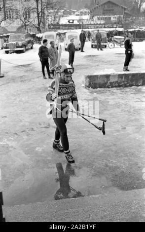 Foto von skirennläufer Toni Sailer mit seinen Skiern auf seinen Schultern auf dem Weg in die Seilbahn auf den Hahnenkamm. Er nahm an das Skirennen gibt es im Januar 1962 statt. Der Hahnenkamm Rennen wurde am Hahnenkamm in Kitzbühel seit 1931. Stockfoto