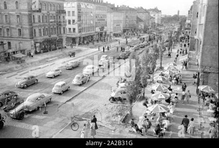 Blick auf die Leopoldstraße in München. Das Bild zeigt den Verkehr auf der Leopoldstraße, auf der unteren, rechten, einer der vielen Straßencafés. Stockfoto