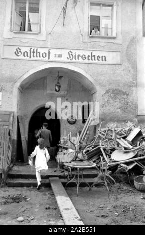 Die Flut in Passau und andere Teile von Niederbayern (Juli, 1954) wurden auch die Flut des Jahrhunderts bezeichnet. Die Donau, der Inn und die Ilz ueber die Ufer übergelaufen, und überflutete Städte und Dörfer. Foto der Bewohner Reinigung und beschädigt Möbel auf der Straße vom Hotel 'Gasthof zum Hirschen'. Stockfoto