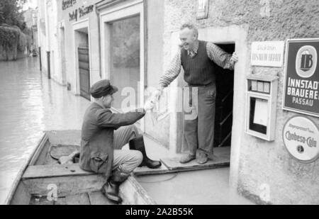 Die Flut in Passau und andere Teile von Niederbayern (Juli, 1954) wurden auch die Flut des Jahrhunderts bezeichnet. Die Donau, der Inn und die Ilz ueber die Ufer übergelaufen, und überflutete Städte und Dörfer. Foto von einem Helfer zur Wiederbelebung der Stadtbewohner in einem Boot. Stockfoto