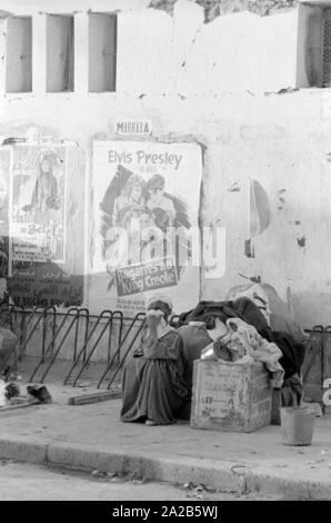 Eine der Überlebenden des Erdbebens auf die Straße. Im Hintergrund, ein Plakat für den Film "King Creole" von Elvis Presley. Bericht 'Erdbeben in Agadir". Die 1960 Agadir Erdbeben zerstört fast die gesamte Stadt und ist die schwerste Naturkatastrophe in der Geschichte Marokkos angesehen. Stockfoto