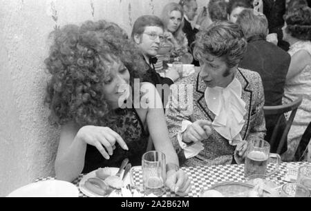 Rudi Carrell mit seiner Frau Anke essen und trinken Bier und GESTIKULIEREND an der Münchner Filmball. Rudi Carrell trägt ein Rüschen Shirt unter seiner Jacke. Stockfoto