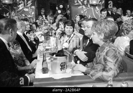 Franz-Josef Strauß (2. von rechts), in der Klage, bei der Filmball München, im Bayerischen Hof. Sie sitzen zusammen mit weiteren Gästen in der Tabelle, die mit gekühltem Sekt und Gläser gefüllt ist. Stockfoto