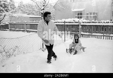 Roberto Blanco spielt im Schnee mit seiner Tochter Mercedes und einem Schlitten im Jahre 1970. Stockfoto