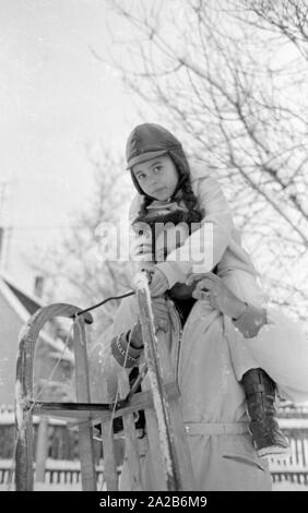 Roberto Blanco spielt im Schnee mit seiner Tochter Mercedes und einem Schlitten im Jahre 1970. Stockfoto