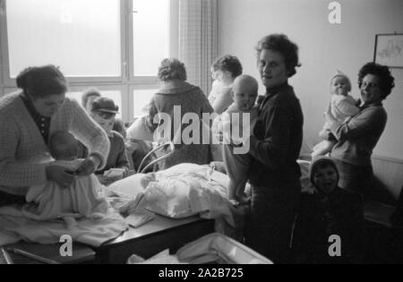 Mütter mit ihren Kindern im Kindergarten in Rimbach. Die Frau in den Vordergrund Windeln ein Baby. Die dorfgemeinschaft Häuser wurden als Teil der Hessenplan unter anderem gebaut, um die Infrastruktur und das kulturelle Leben in ländlichen Gebieten zu verbessern. Stockfoto