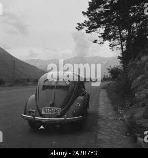 Eine frühe VW Käfer mit bayerischen Kennzeichen auf einem Mountain Road. Charakteristisch für die frühen Jahre Käfer sind die kleinen Rückleuchten und der geteilten Heckscheibe (' Brezel Käfer"). Stockfoto