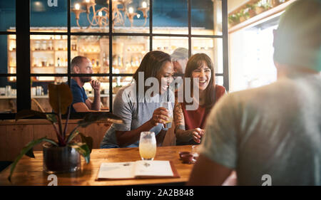 Junge Freunde lachen über diverse Getränke in einer Bar Stockfoto