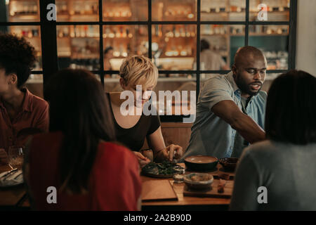 Vielfältige Gruppe von Freunden in einem Bistro Essen bei Nacht Stockfoto