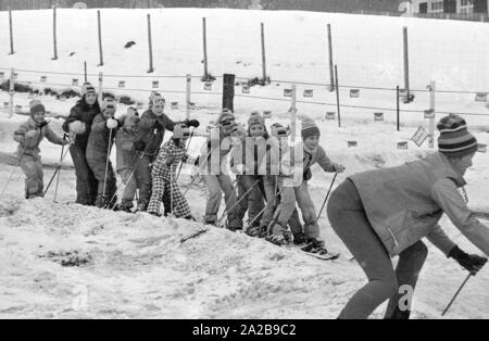Kinder in den Skikurs in der Skischule Garmisch. Die Firma "Marker" wirbt für seine Sicherheit Skibindungen mit Banner. Stockfoto