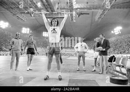 Fußballspieler Franz Beckenbauer plantscht im Gewichtheben am Sportpressefest in der Münchner Olympiahalle. Links im Bild, der Athlet und Moderator Erhard Keller. Stockfoto