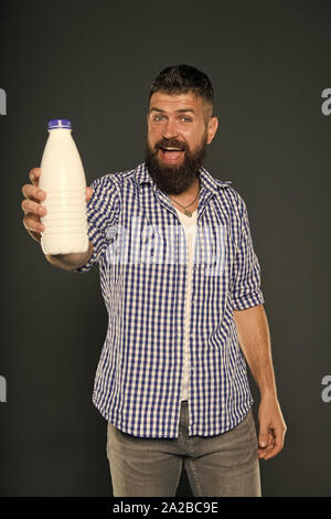 Das beste Getränk für Ihren Körper. Der bärtige Mann hält eine Flasche Milch trinken auf grauem Hintergrund. Happy hipster lächelnd mit natürlichen gesunden Milch trinken. Kaukasische Kerl genießen Sie frischen Joghurt Drink. Stockfoto